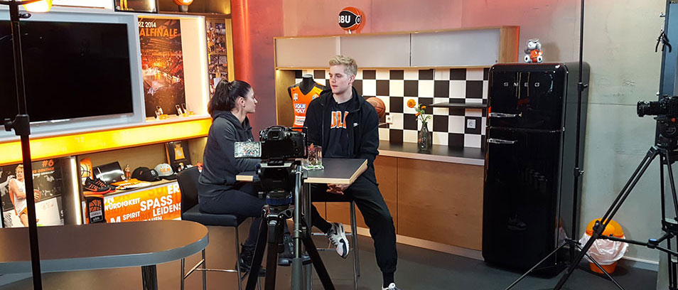 Auf der Abbildung sind eine Frau und ein Mann zu sehen, die sich vor einer Kamera über Ernährung unterhalten.