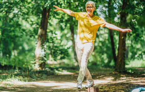 Ältere Frau balanciert auf Baumstämmen