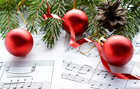 Rote Weihnachtskugeln liegen auf einem Notenblatt