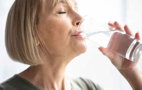 ältere Frau trinkt ein Glas Wasser