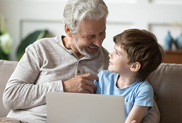 Opa und Enkel schauen sich etwas auf dem Laptop an