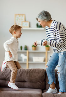 Oma tanzt mit Enkel auf dem Sofa