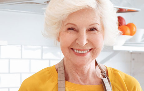 ältere Frau mit Schürze in ihrer Küche