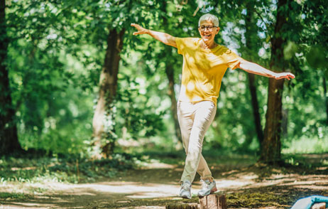 Koordinationsübungen Frau balanciert auf Baumstumpfen