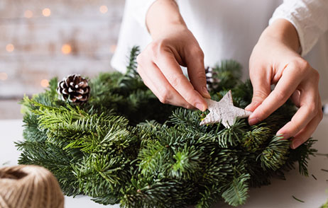 eine Frau dekoriert einen Adventskranz