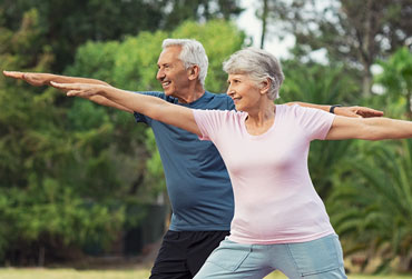 ältere Frau und Mann bei einer sportlichen Bewegung im Freien