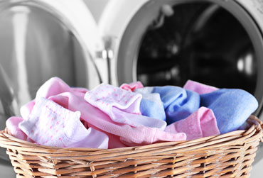voller Wäschekorb steht vor der Waschmaschine