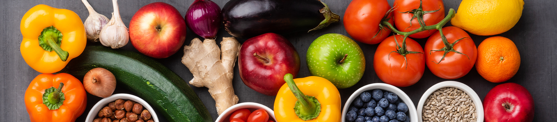 Verschiedende Obst- und Gemüsesorten liegen auf einem grauen Tisch