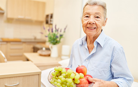 Lächelnde ältere Frau mit einer Schüssel Obst in der Hand