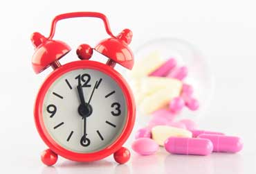 roter Wecker und Kapseln im Hintergrund