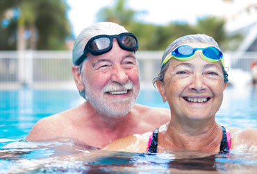 älteres Paar beim Schwimmen im Pool