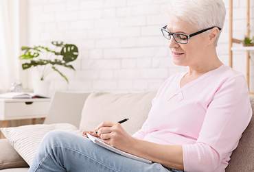 ältere Frau schreibt in ein Notizblock