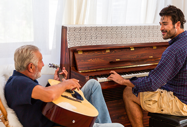 Vater und Sohn spielen zusammen Gitarre und Klavier