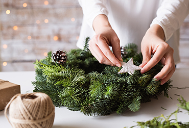 Eine Frau bindet einen Adventskranz