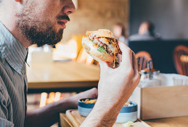 Fast Food macht vergesslicher Mann isst einen Burger