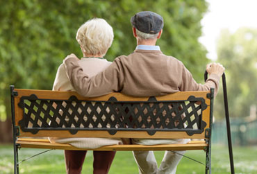 altes Paar sitzt auf einer Parkbank 