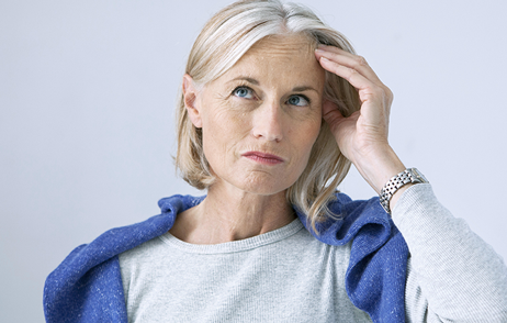 Frau hebt sich die Hand an die Stirn und denkt nach