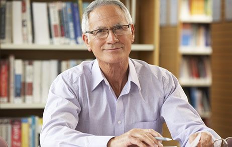 älterer Mann sitzt in der Bibliothek
