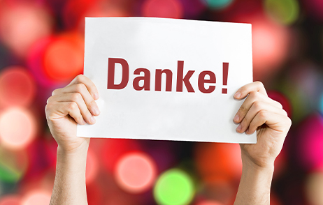Ein Schild mit dem Wort "Danke!" wird von zwei Händen in die Höhe gehalten