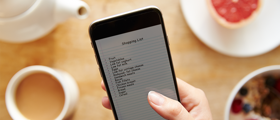 Smartphone in Alltagssituation, auf dem Display eine Shopping Liste