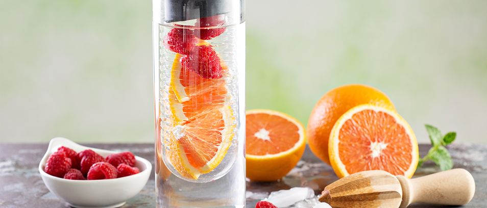 Wasserkaraffe mit sprudelndem Wasser und Früchten gefüllt