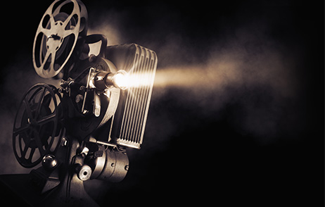 Kino-Quiz Alte Filmkamera, die eingeschaltet ist. Der Hintergrund ist schwarz.