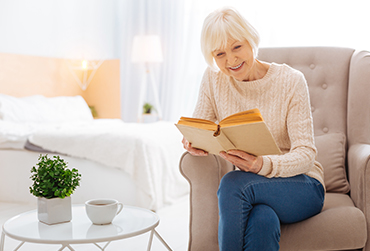 Winter-Unternehmungen fürs Gedächtnis Eine ältere Dame sitzt im Sessel und liest ein Buch