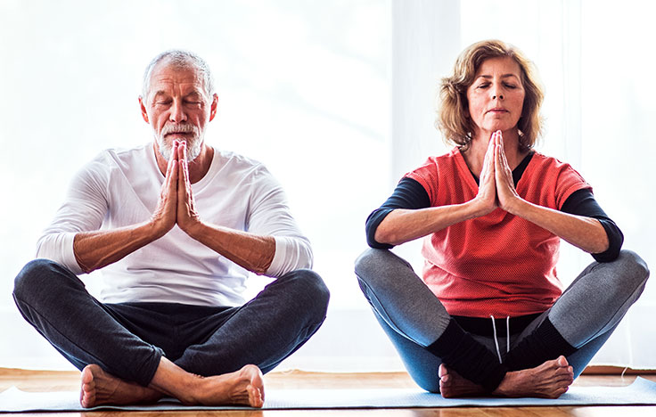 Sommerfit: Bewegung im Freien älteres Paar macht zusammen Yoga